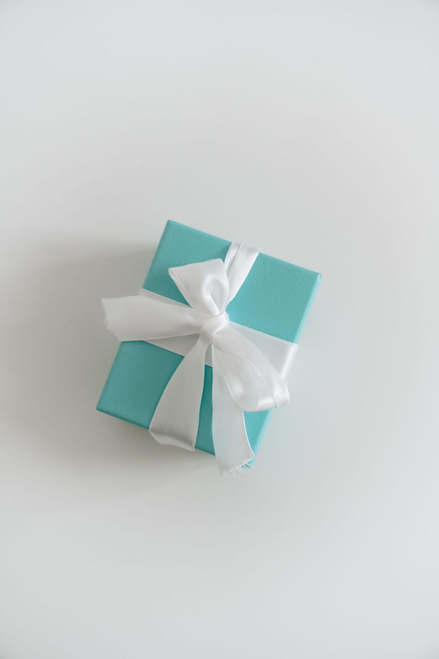 A small mint-green gift box tied with a white ribbon