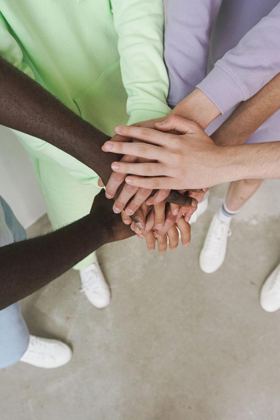 A circle of hands, different skin tones, stacked one on top of another