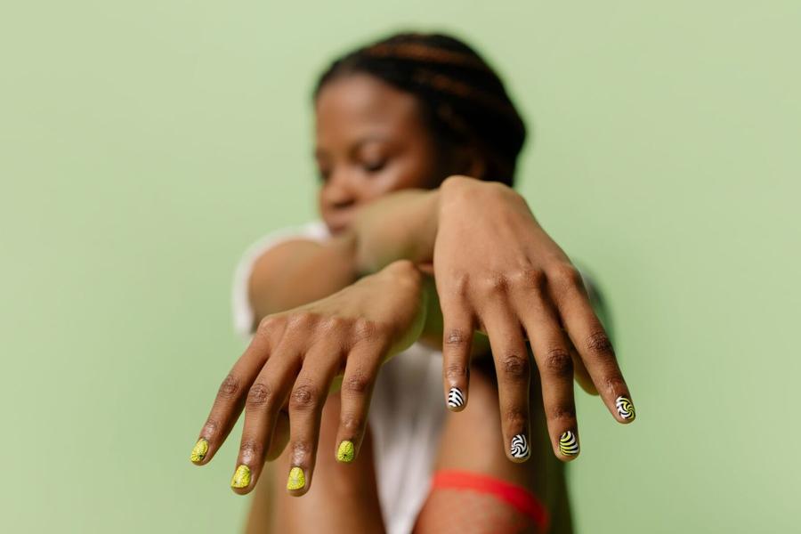 Long painted nails on a model’s hands against a sage backdrop